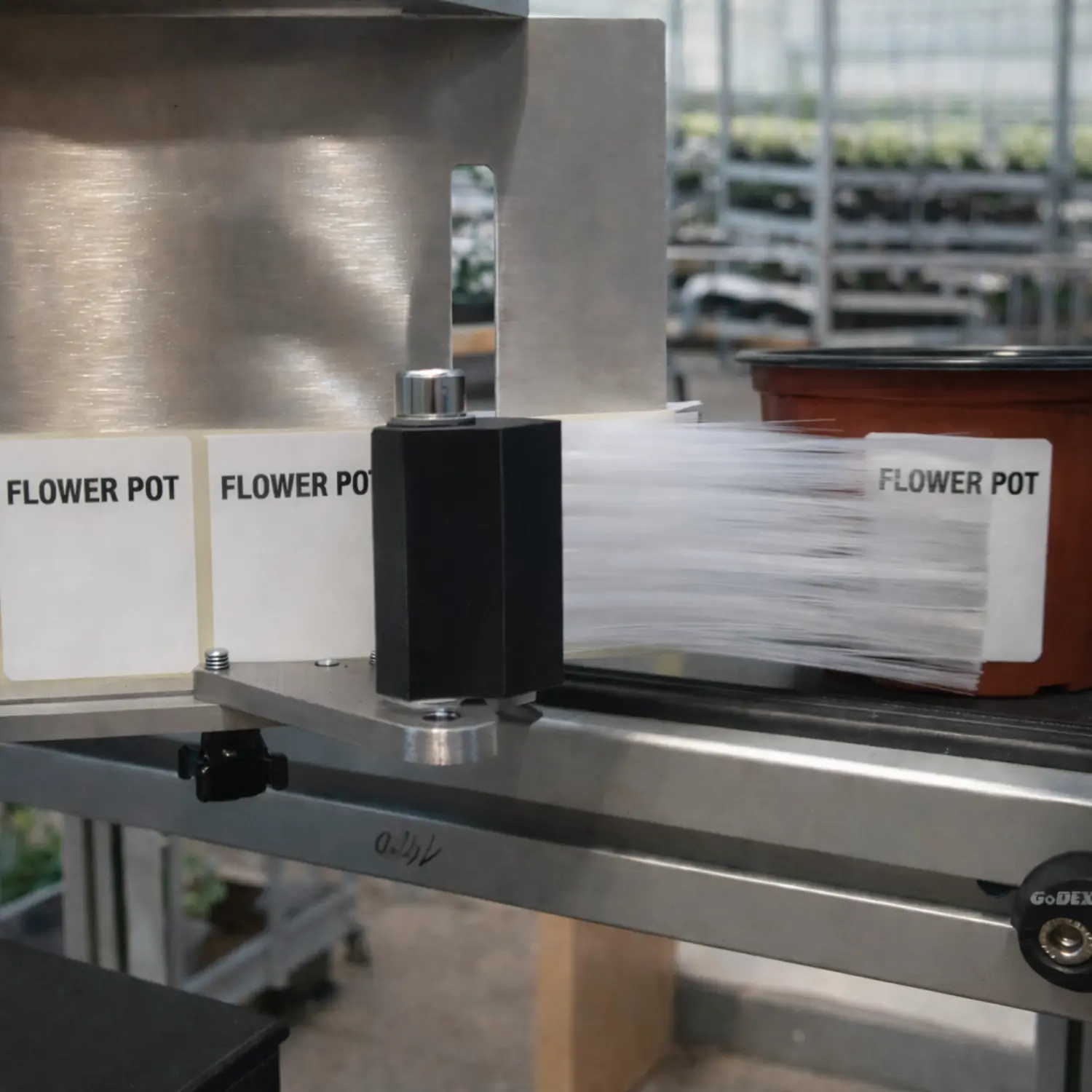 Close-up of a pot labeling machine and label applicator during operation